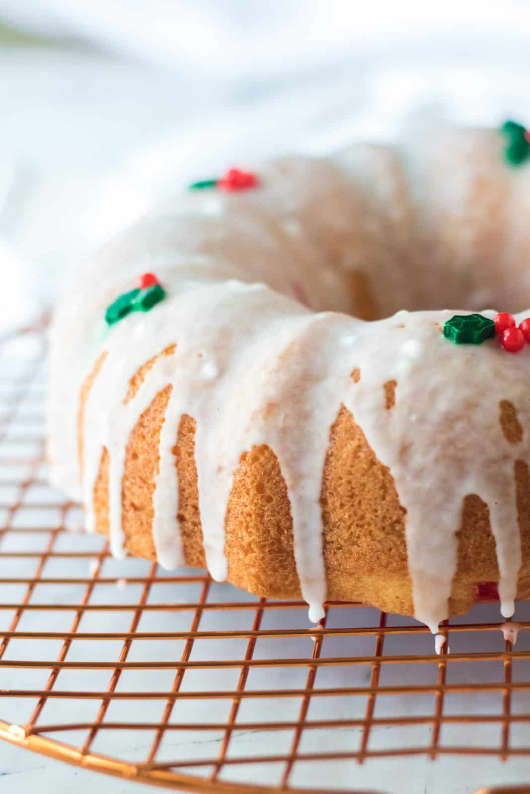 icing shown drizzled over baked bundt cake with holiday sprinkles on top.