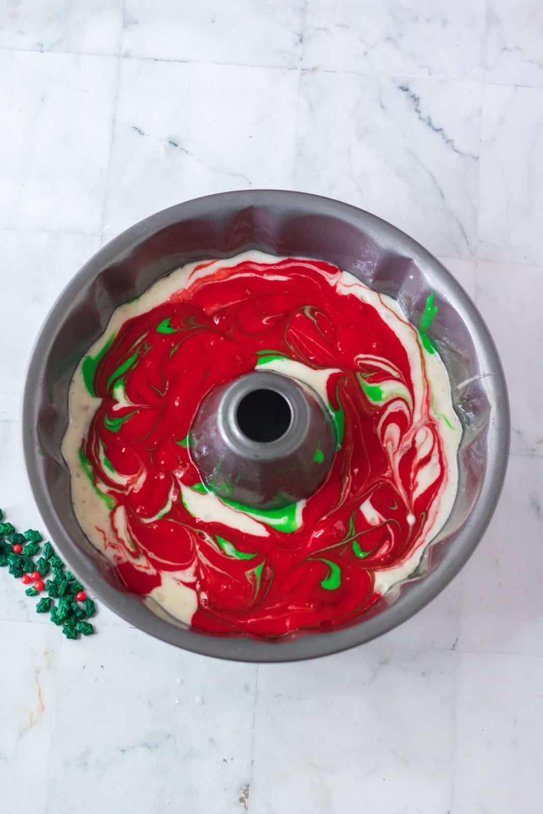 cake batter shown in a bundt pan with the red, white and green colors swirled together. 