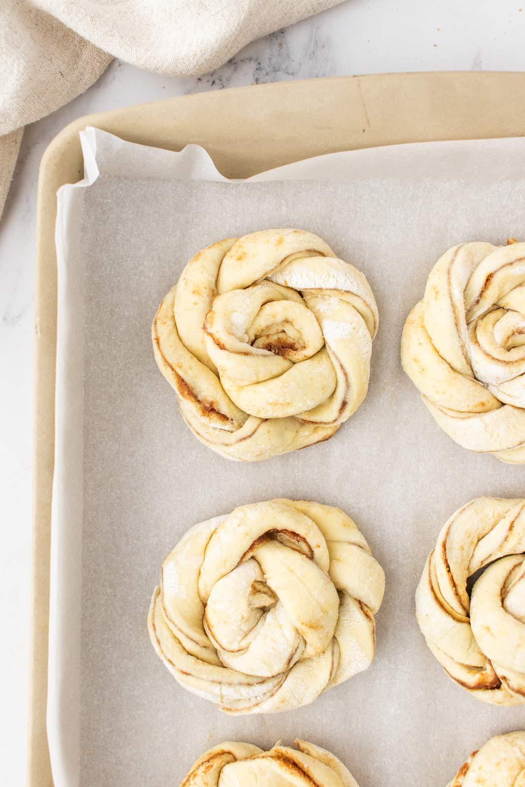 rolled up puff pastry shaped into a knot on a parchment paper lined baking sheet. 