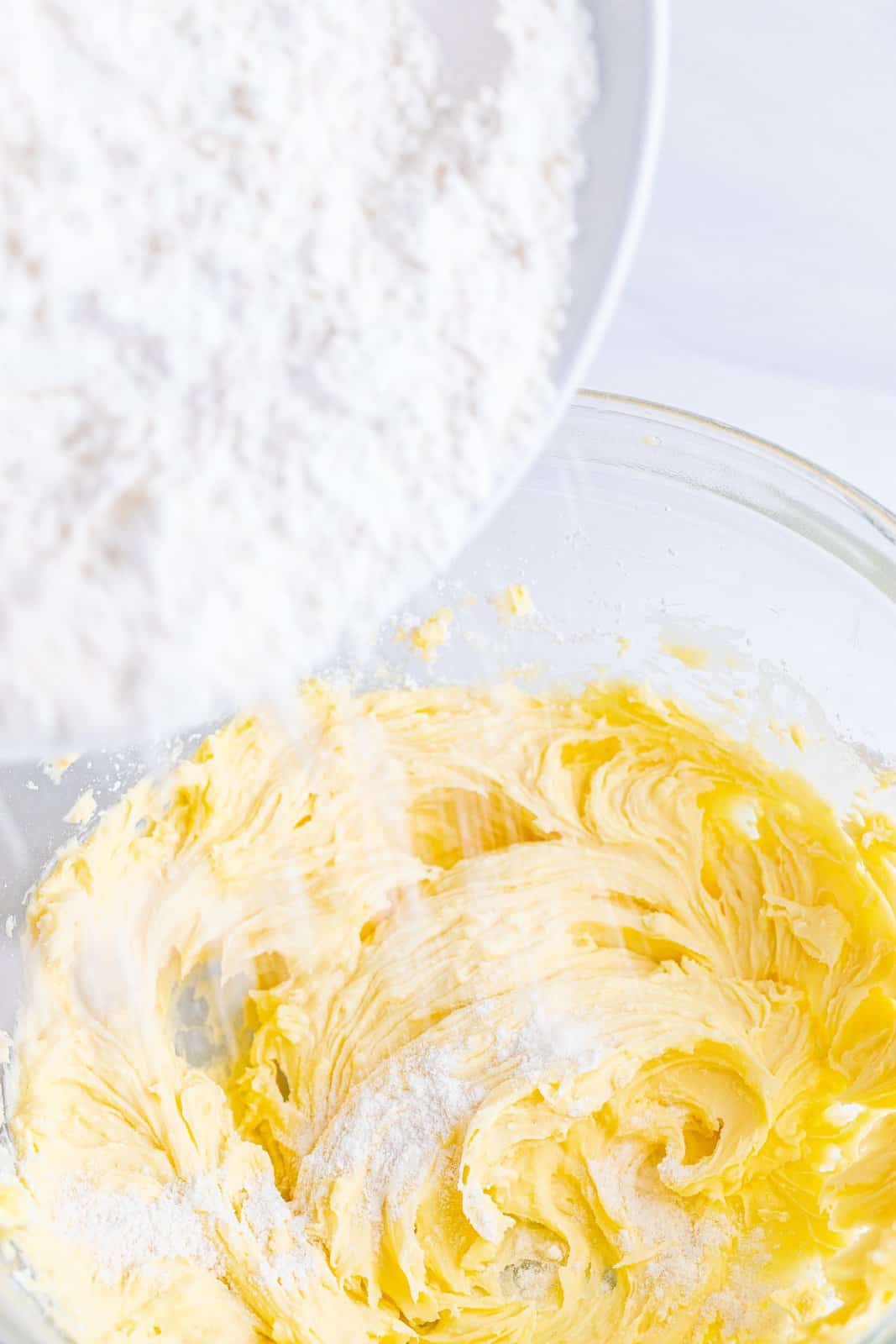 pouring flour mixture into butter shortening mixture in a bowl. 