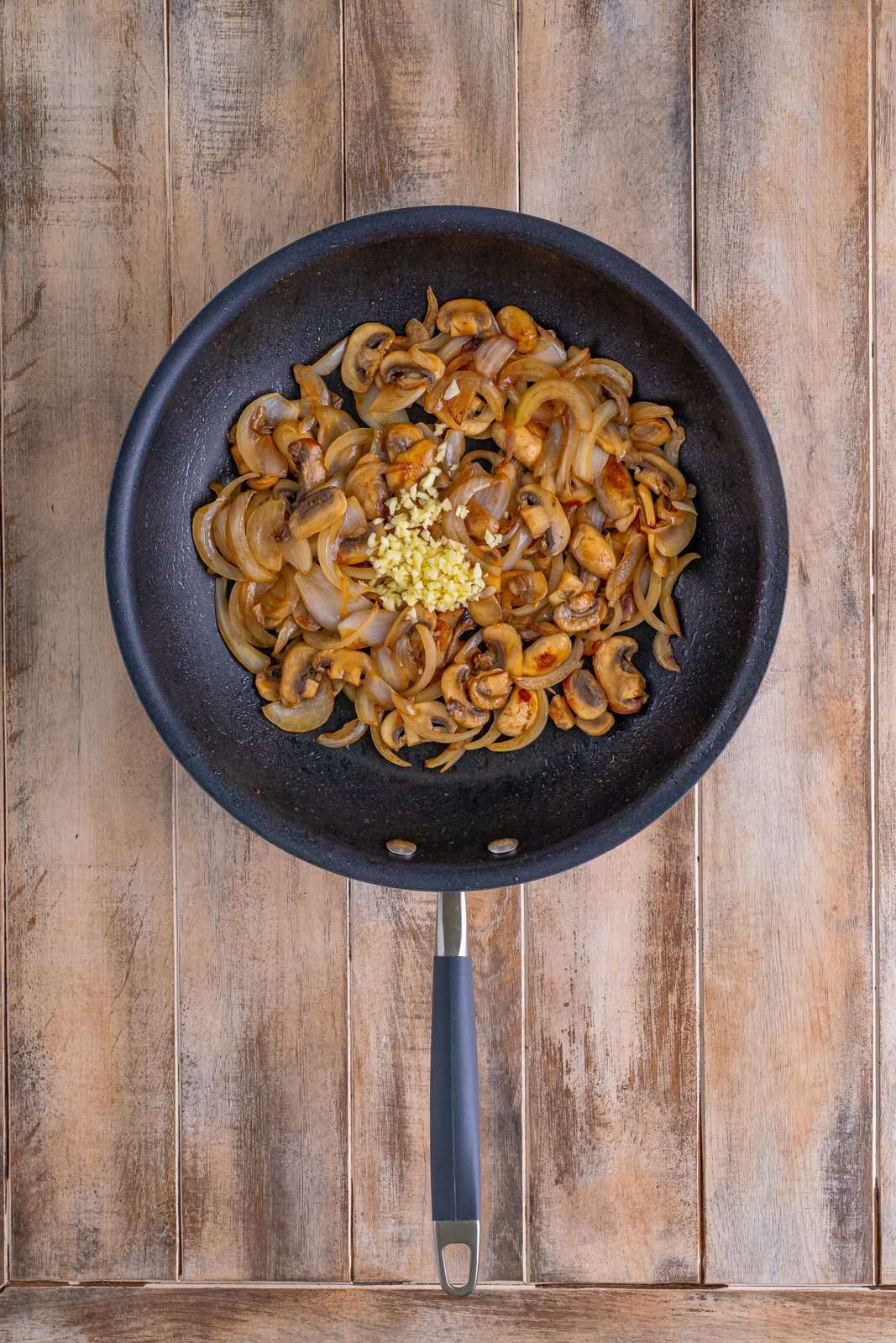 minced garlic added to onions and mushrooms in a skillet. 