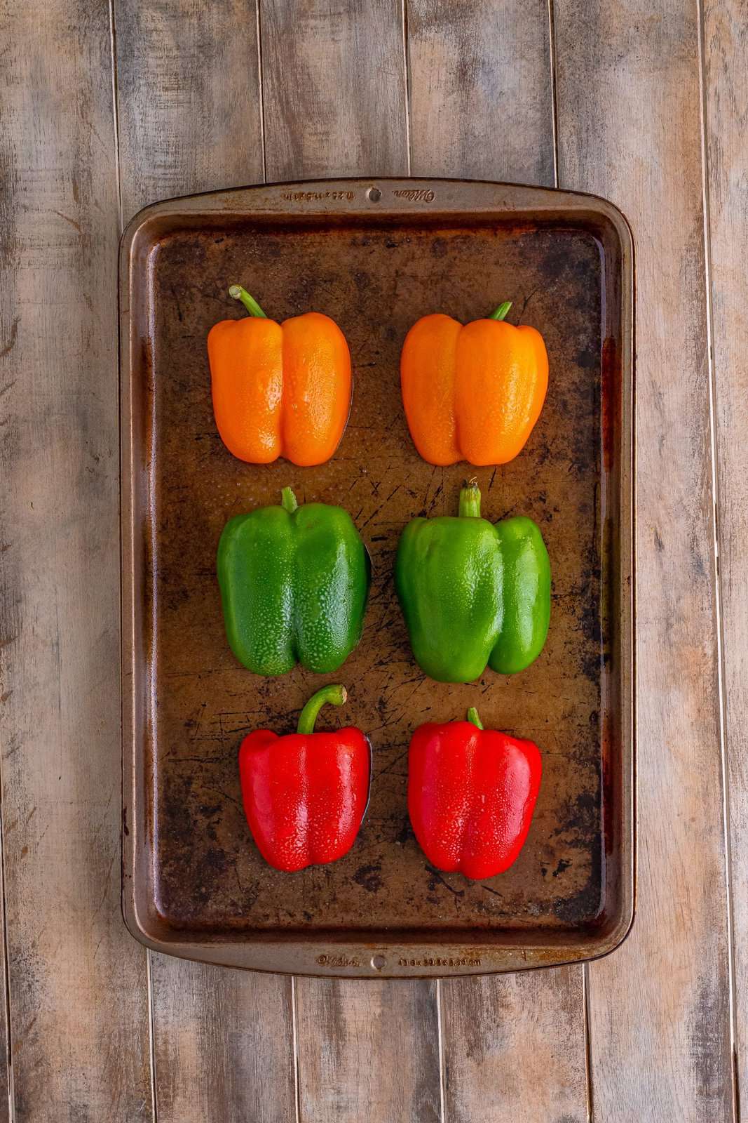6 bell peppers sprayed with nonstick cooking spray on a baking sheet. 