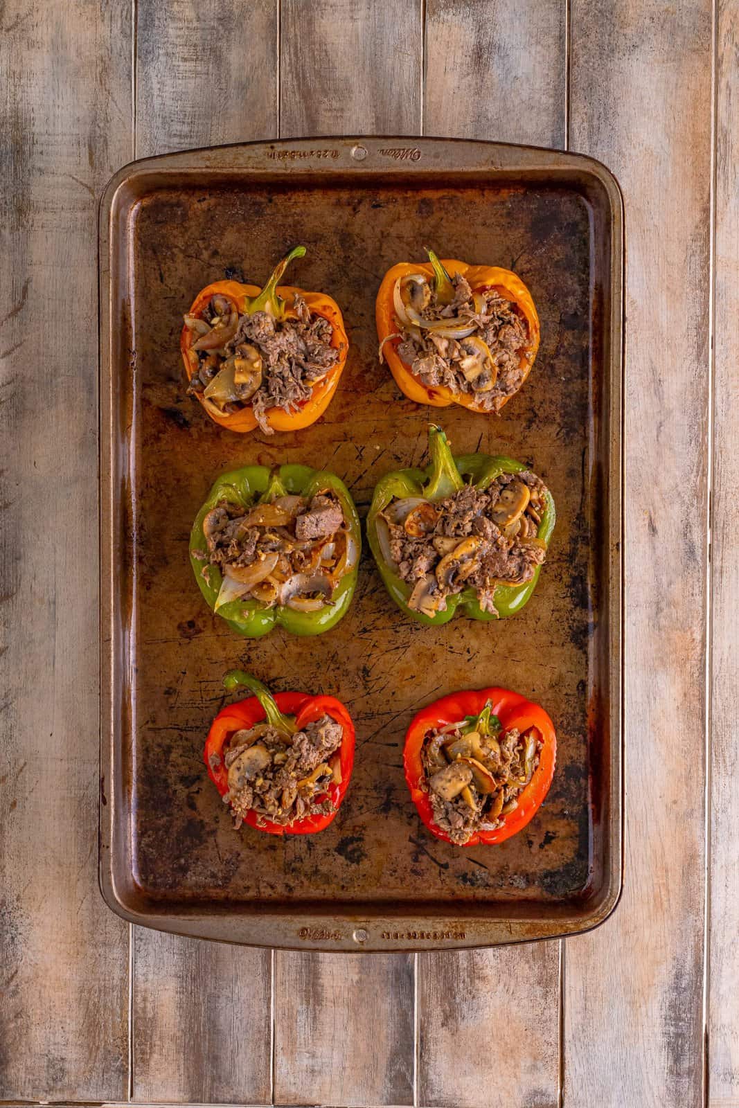 cheesesteak mixture showed stuffed into baked bell peppers on a baking sheet. 