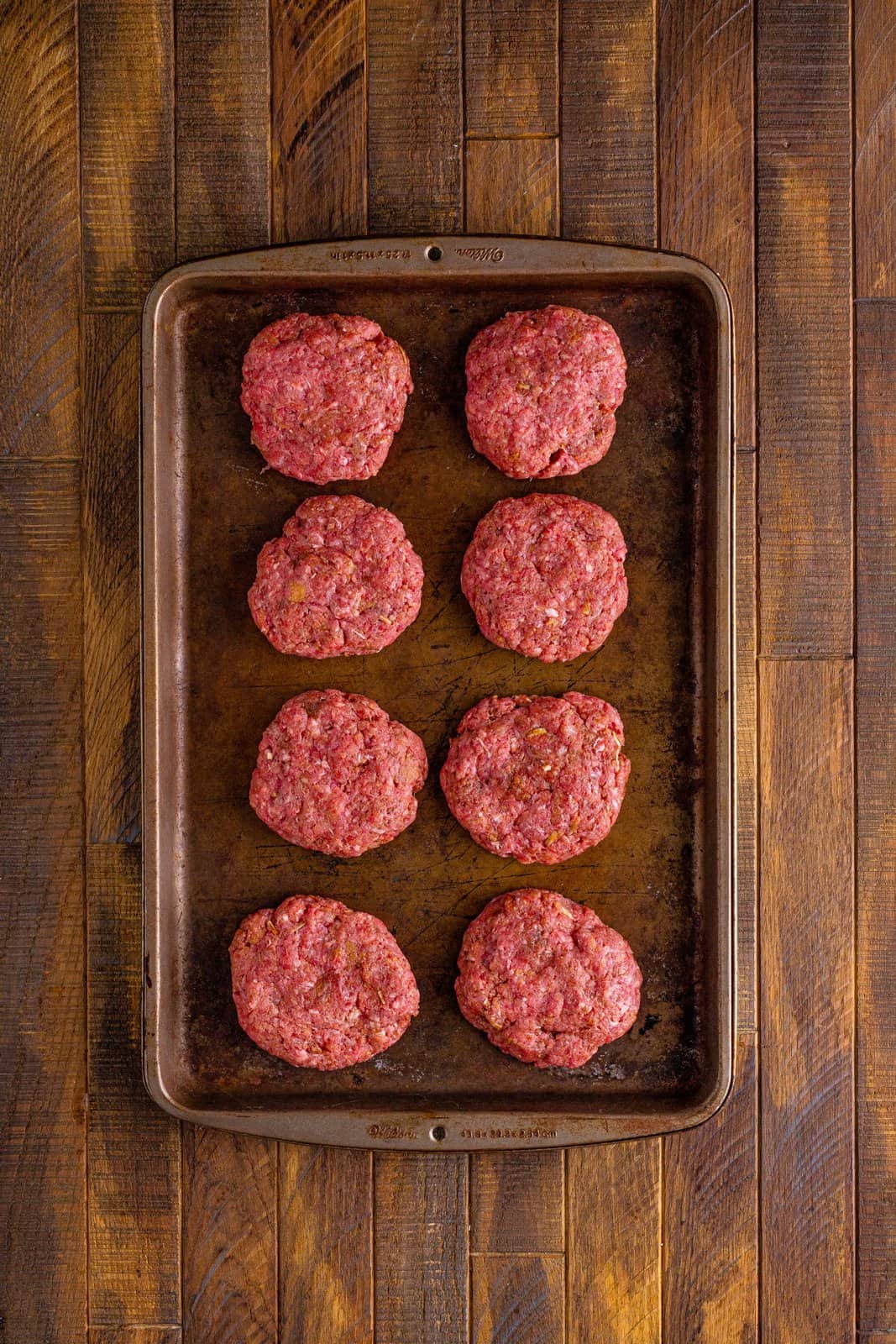 with grand beef patties show on a baking sheet. 