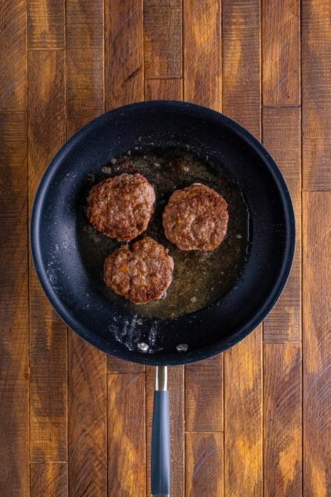 browned hamburger patties shown in a skillet.