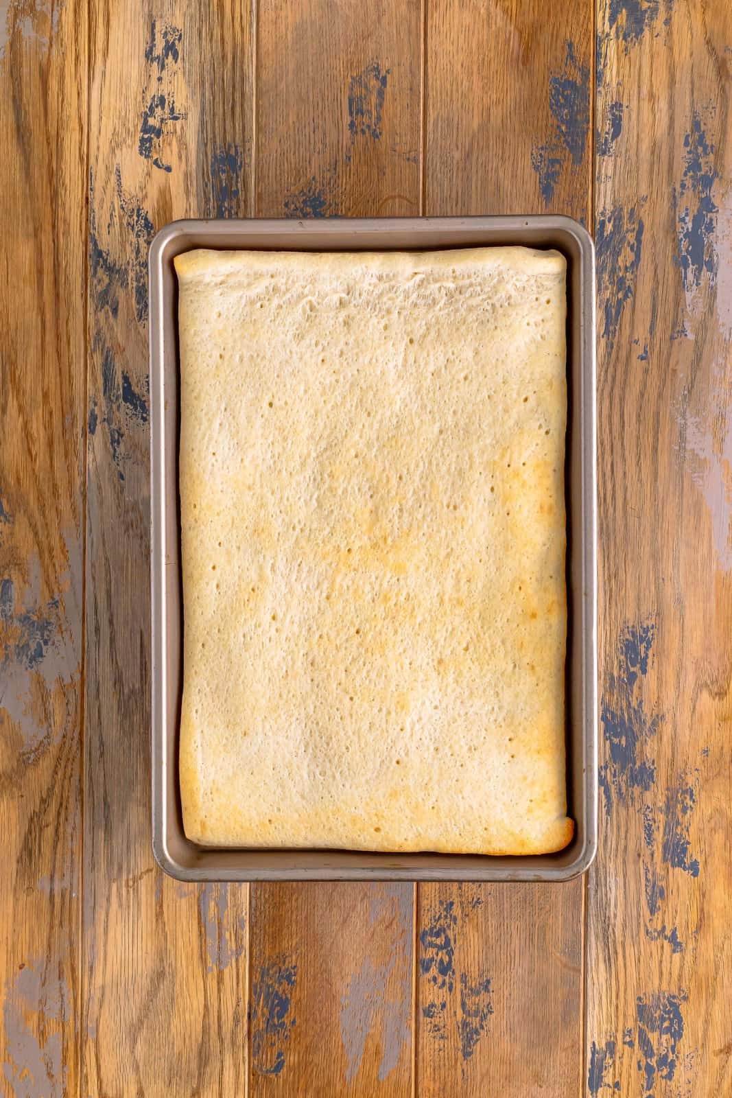 pre baked pizza dough in a rectangle baking pan.