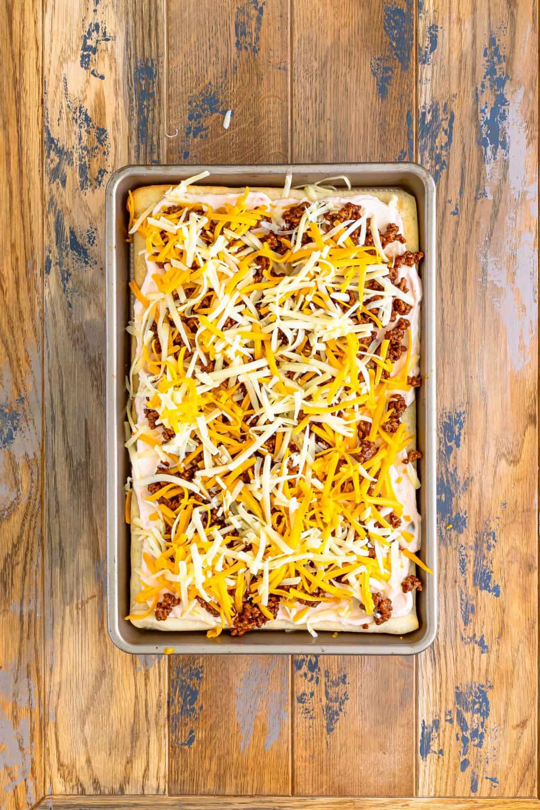 shredded cheddar and Monterey Jack cheeses evenly sprinkled on top of taco pizza.