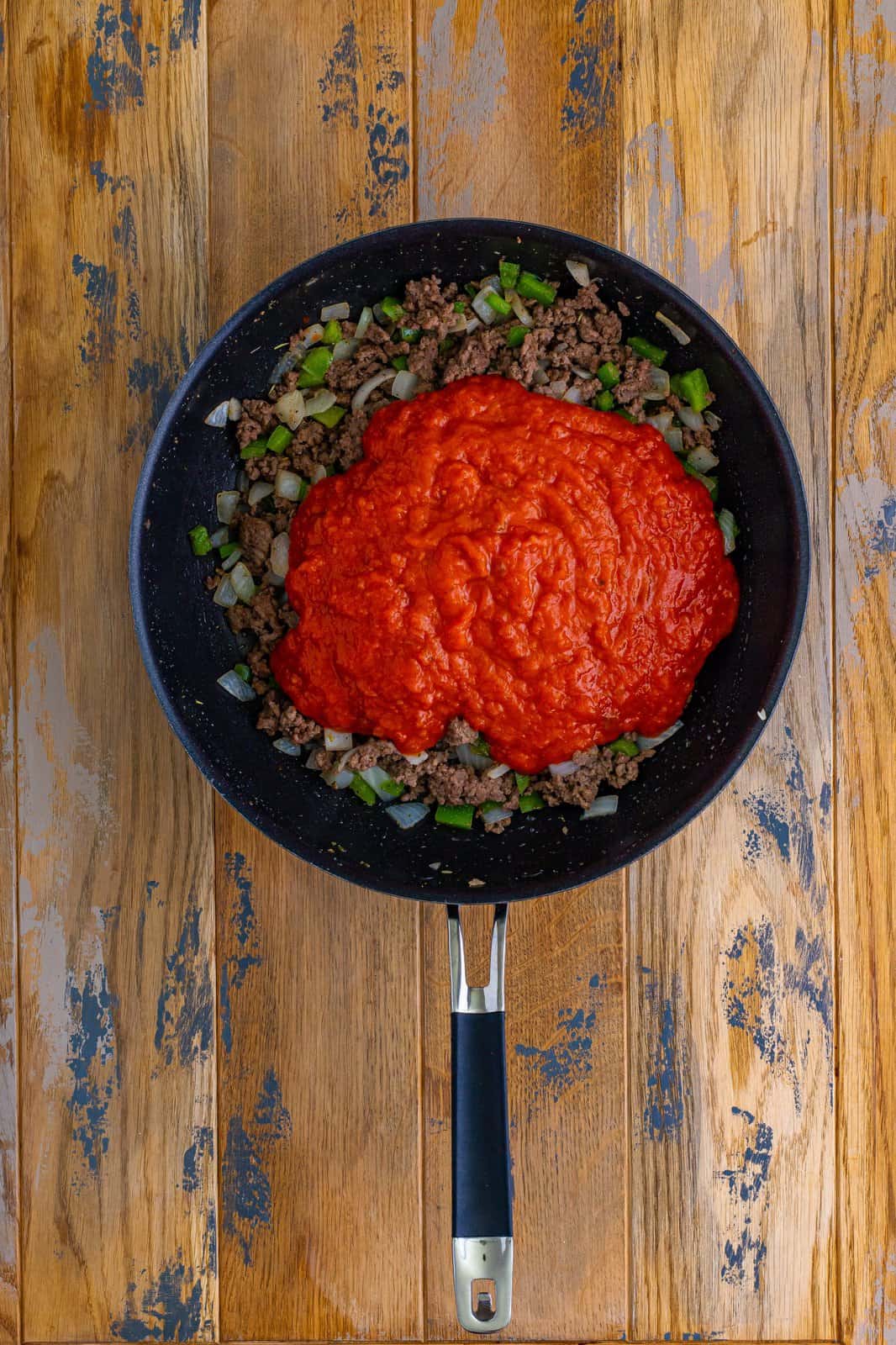 marinara sauce added to cooked ground beef in a large skillet. 