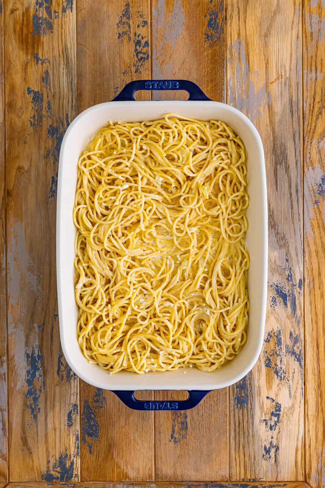 alfredo sauce and cooked spaghetti mixture poured into the bottom of a baking dish. 