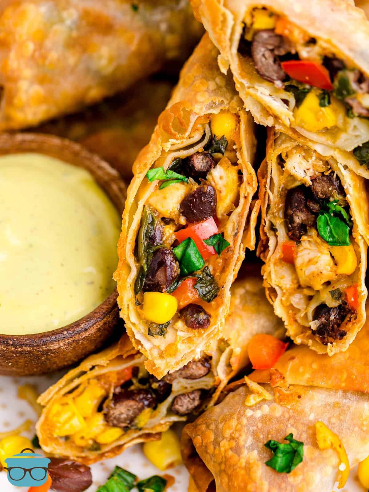 Close up on two open Southwestern Egg Rolls and a yellow dipping sauce.
