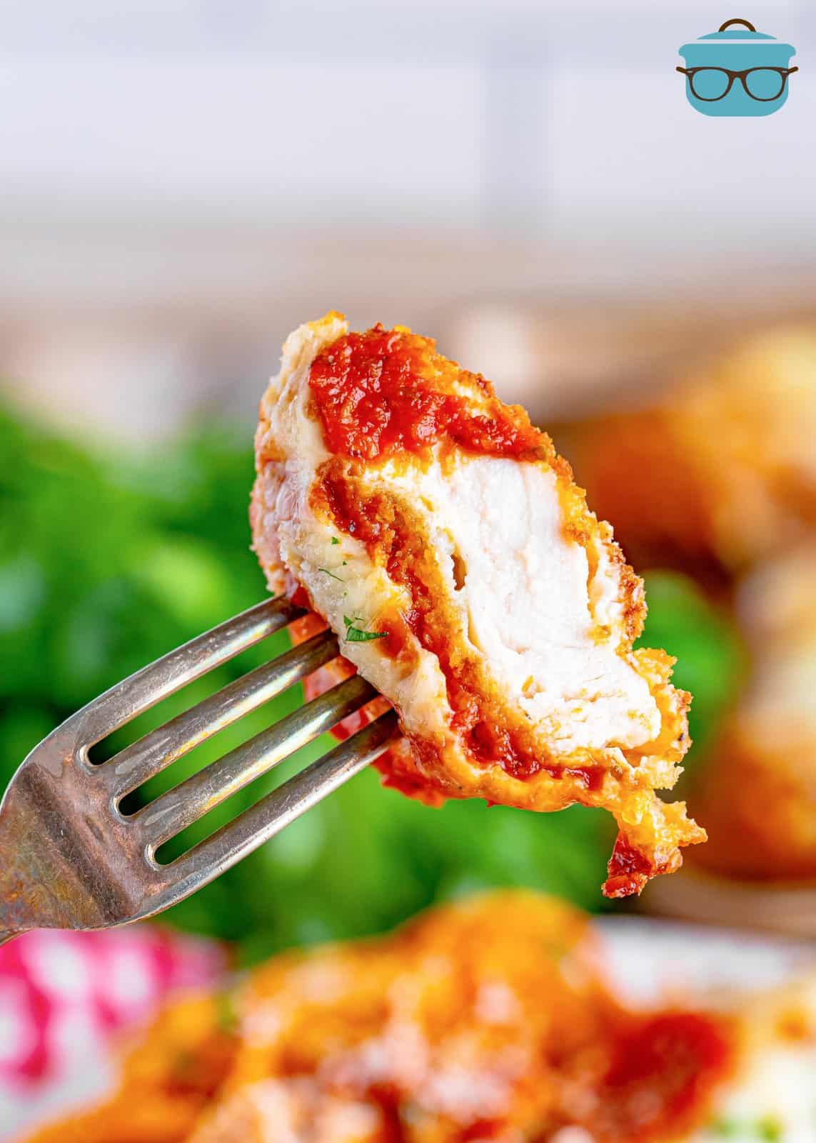 A fork holding a bite of homemade chicken parmesan.