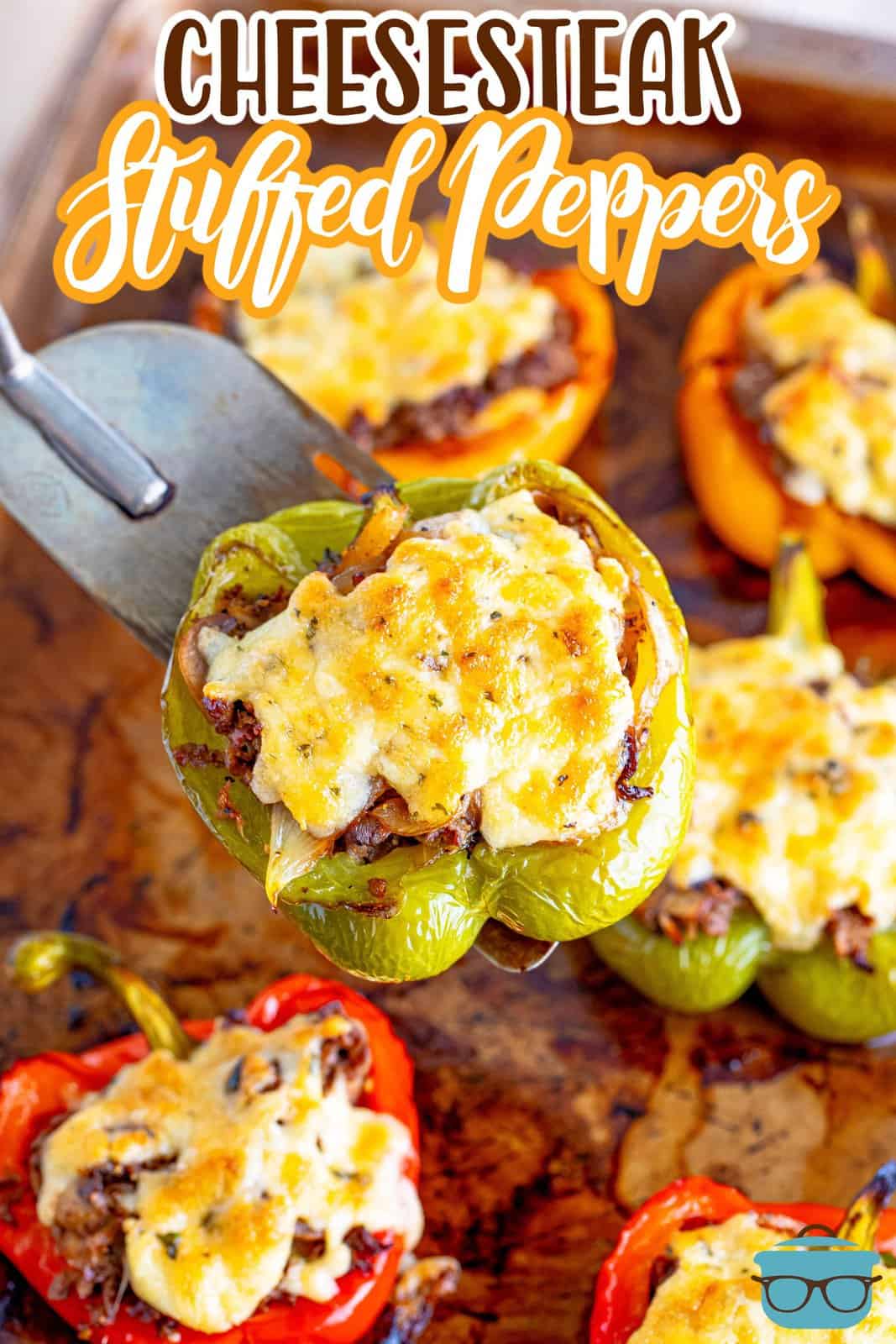 cooked stuffed bell peppers on a baking sheet with a spatula holding up one of the stuffed peppers over the tray. 