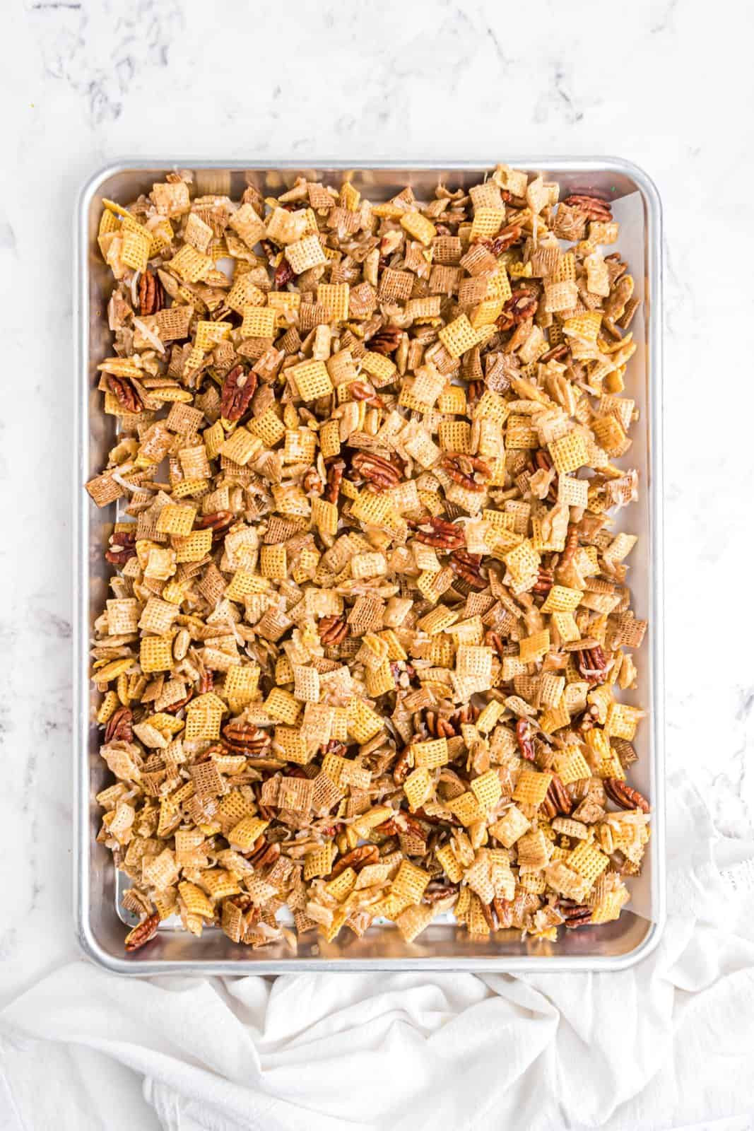 Chex mixture spread over parchment lined pan.