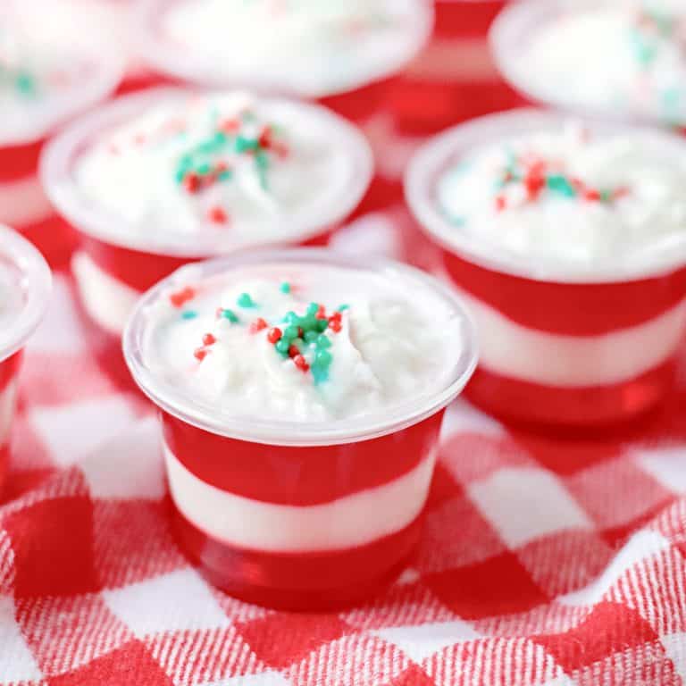 Square image of finished garnished Candy Cane Jell-O Shots on red and white linen.
