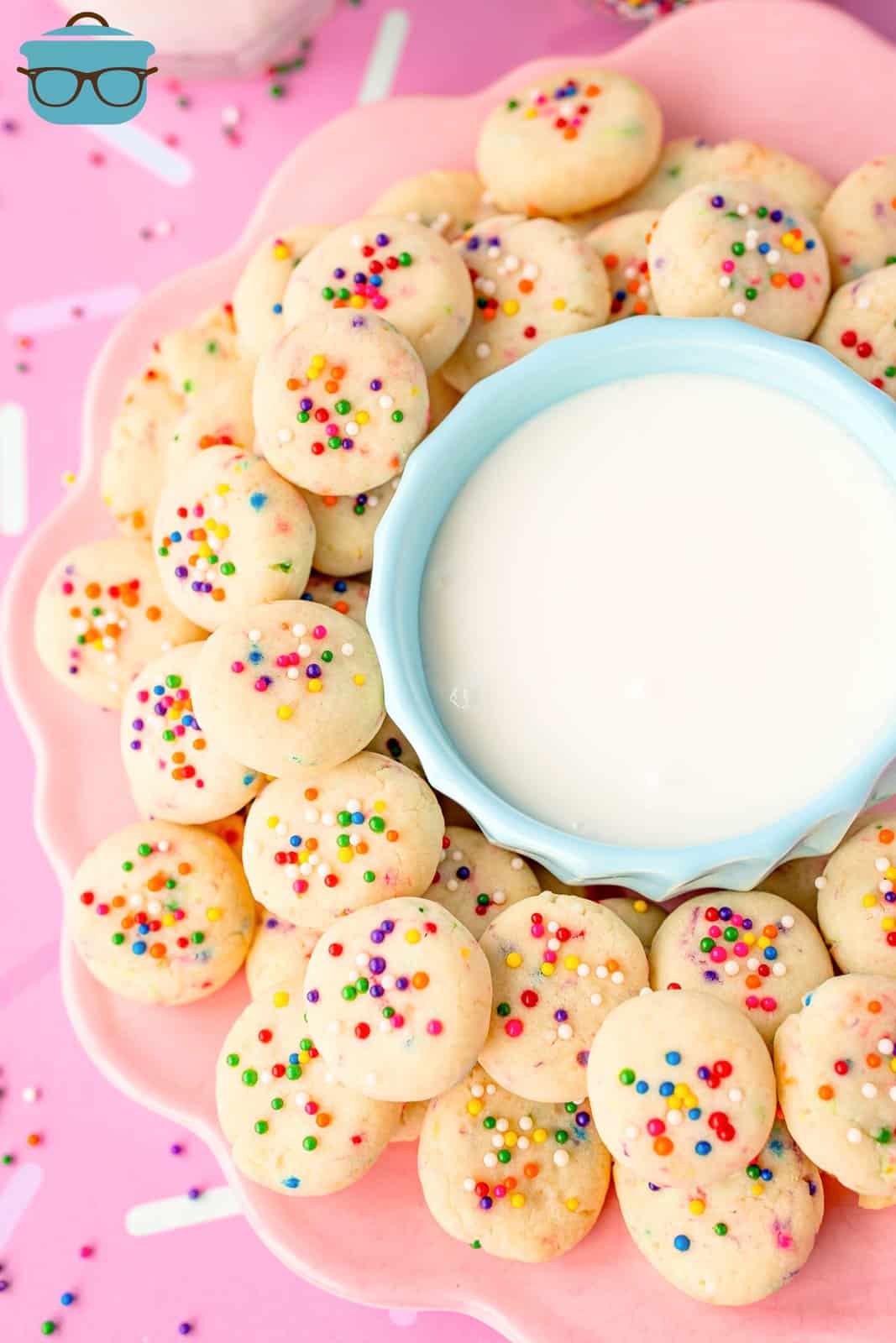 A bowl of frosting surrounded by mini cookies. 