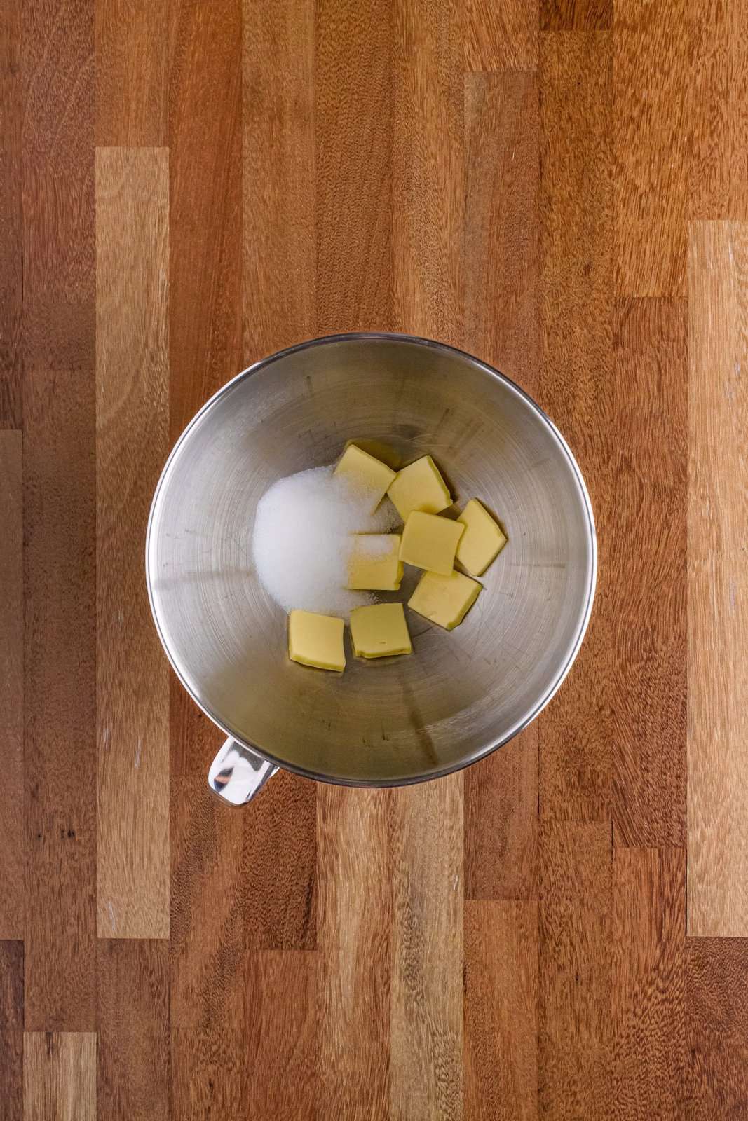 Bowl of a stand mixer butter slices and sugar.