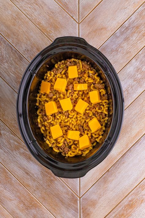 Cubed up Velveeta cheese on top of food in a crockpot.
