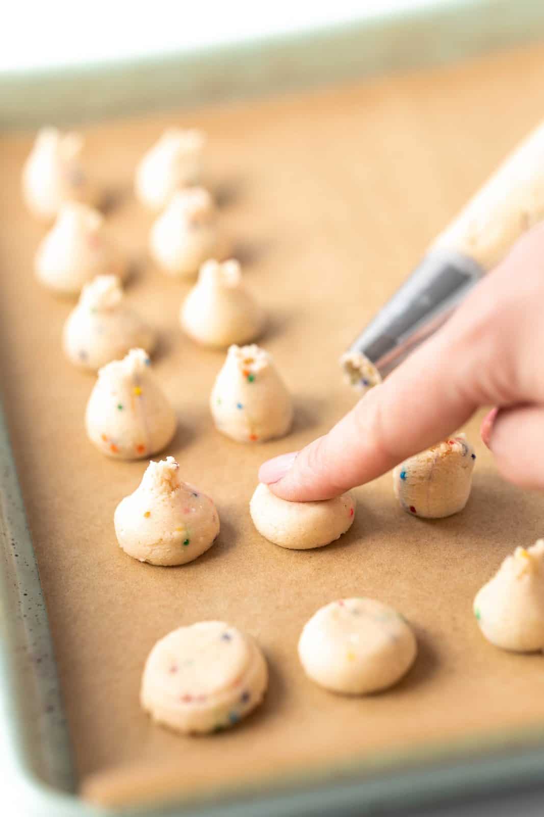 A finger pressing down on cookie dough spots.
