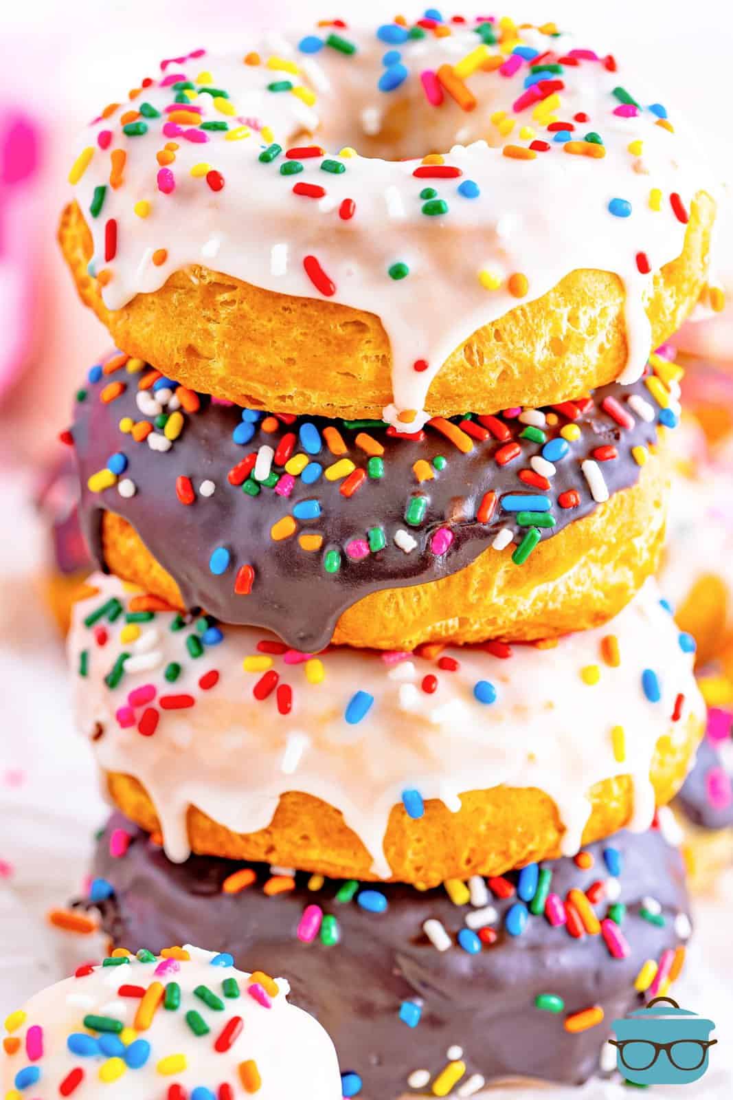 A stack of homemade frosted Air Fryer Biscuit Donuts with sprinkles.