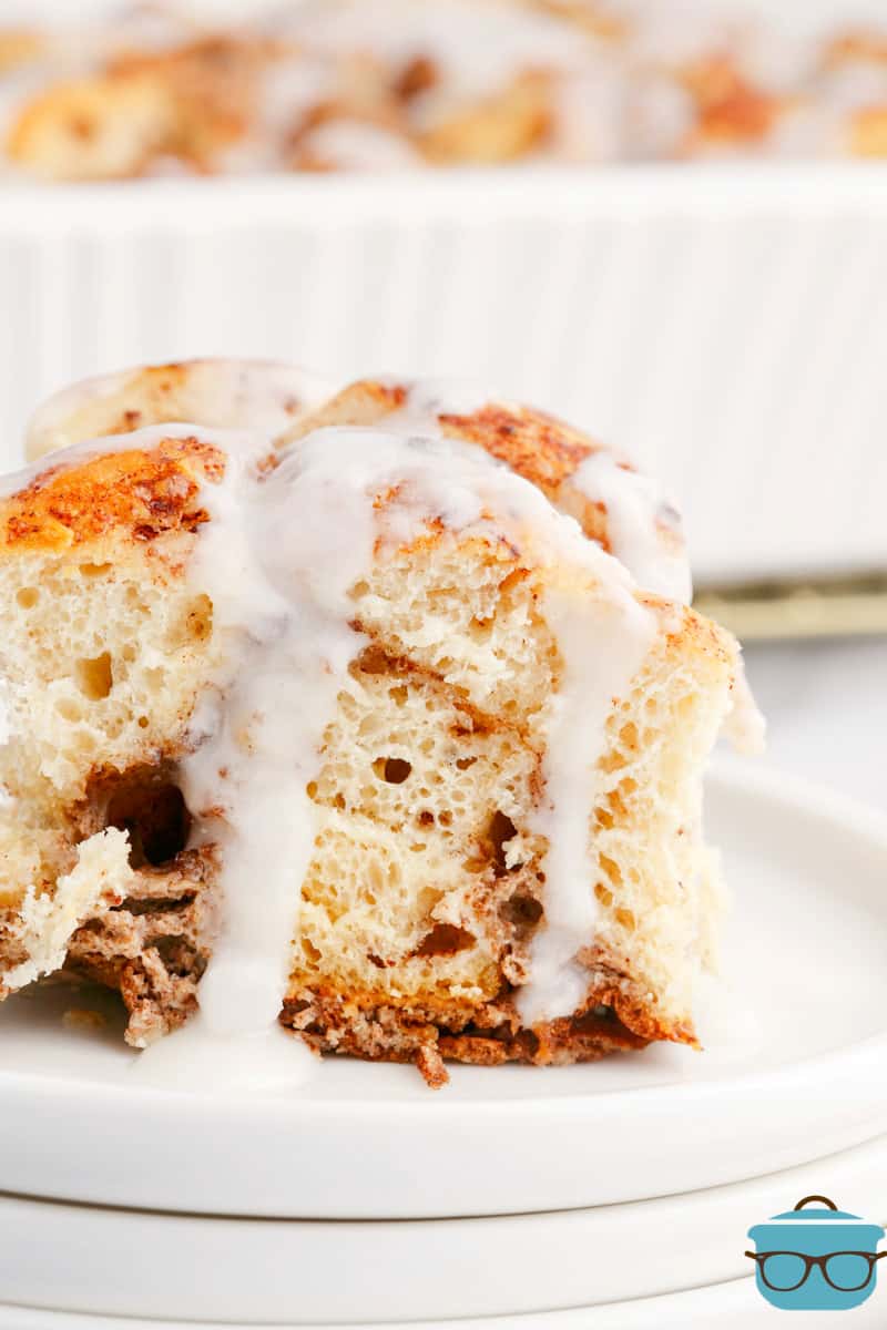 A plate with a serving of Cinnamon Bun Casserole with icing dripping.