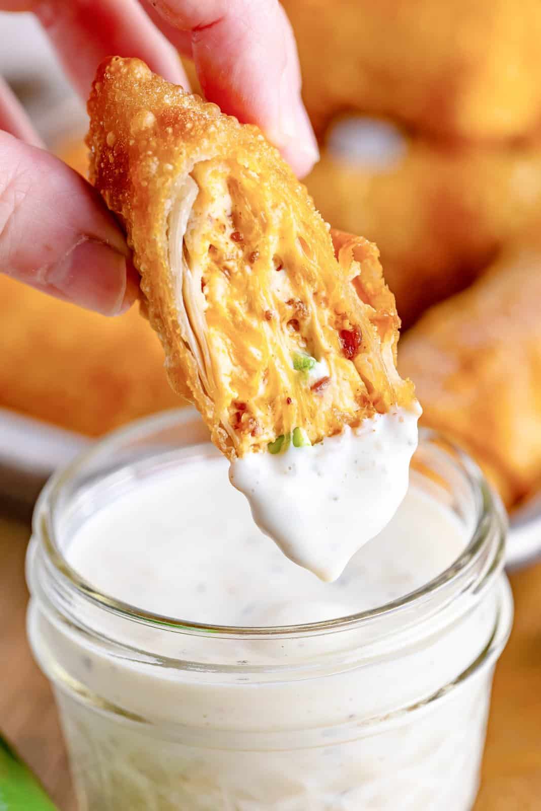 A jalapeno popper egg roll dipped in ranch sauce.