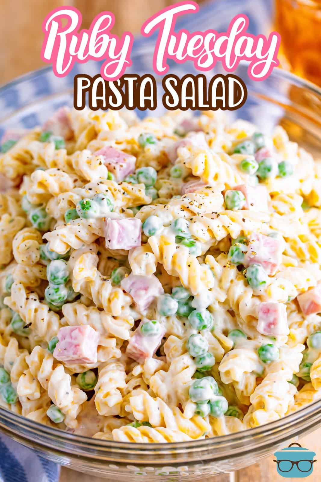 A glass bowl of rotini, pasta, ham, and sauce.