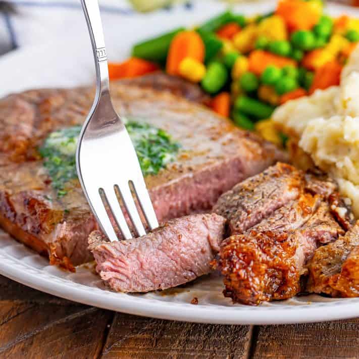 A fork standing in a slice of Ribeye steak.