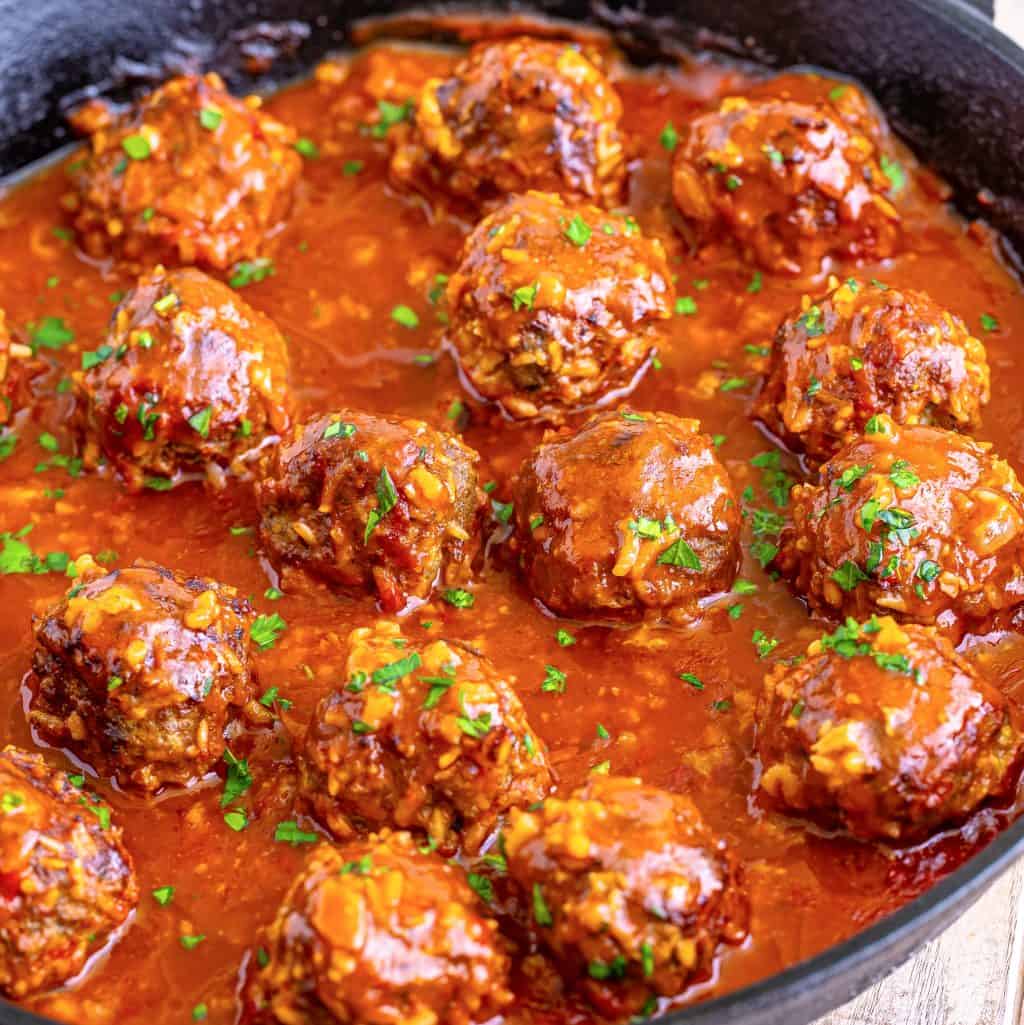 A closeup of a skillet of homemade meatballs in sauce.