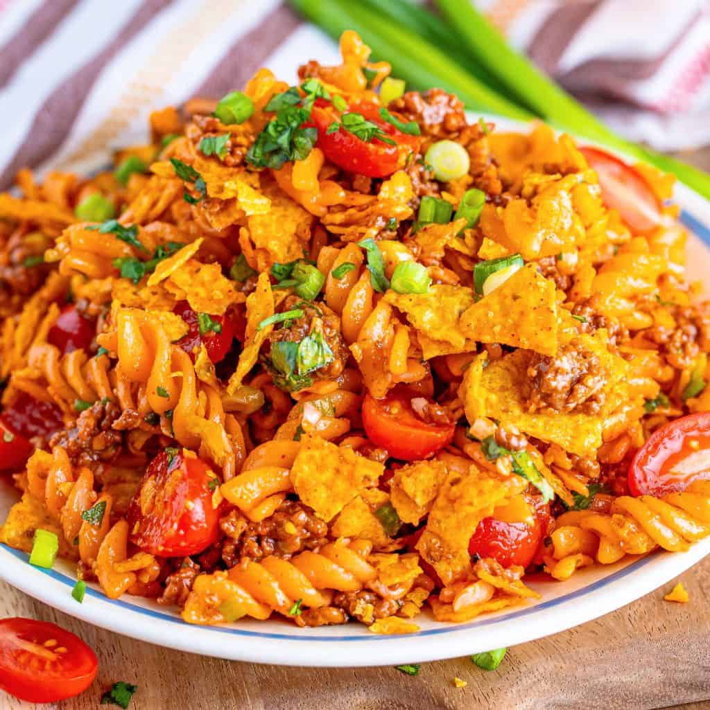 A plate of taco pasta salad with doritos crumbled on top.