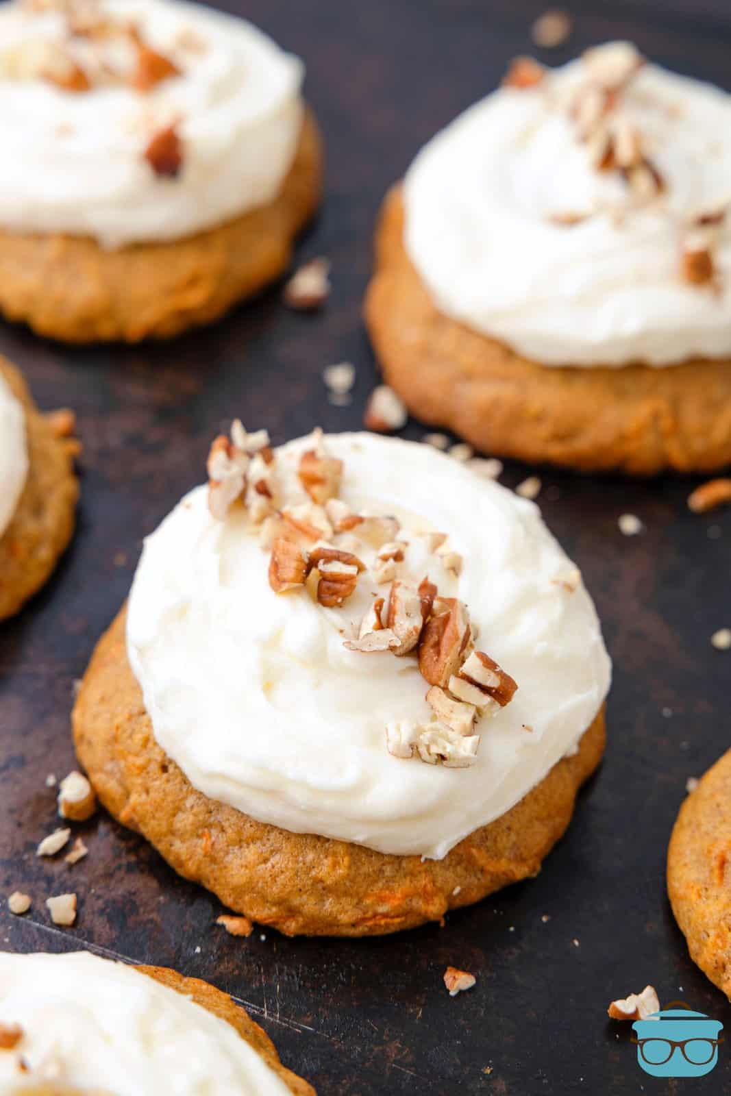 Looking down on a few Carrot Cake cookies with frosting and chopped nuts.