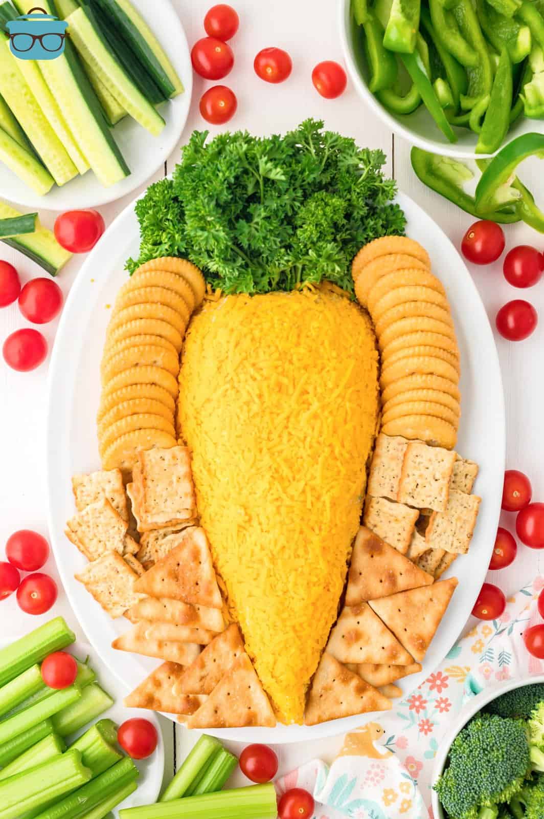 An Easter Carrot Cheeseball on a platter with cracker sand cheeses. 