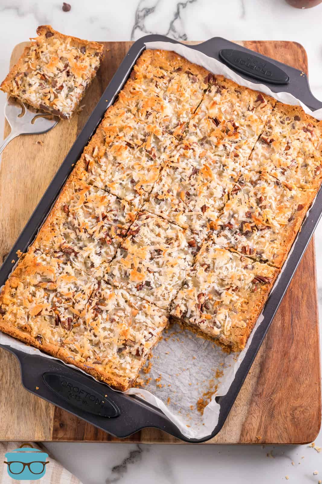 A sheet pan of Magic Cookie Bars with one taken out.