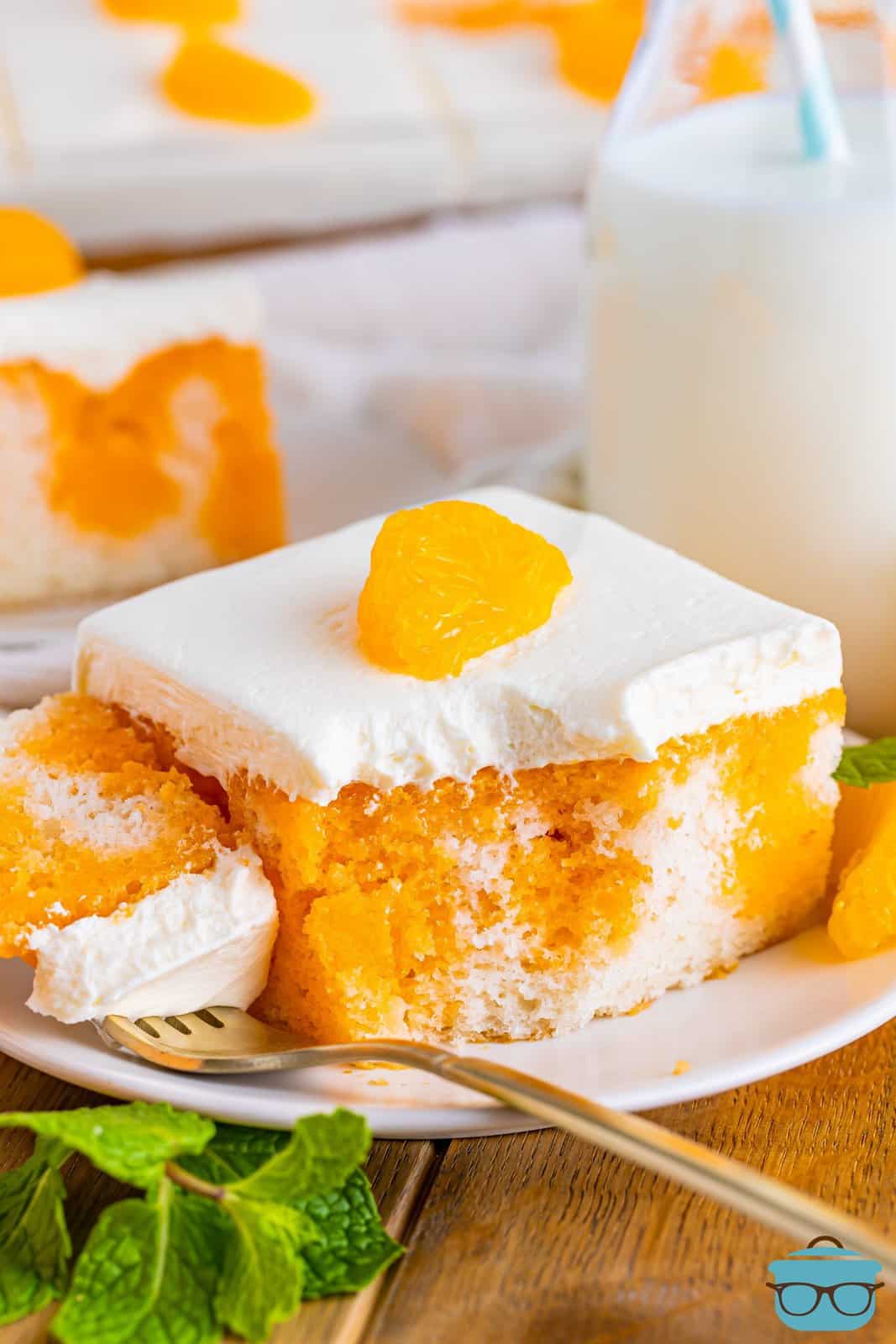 A slice of Orange Creamsicle Poke Cake with a forkful taken out.