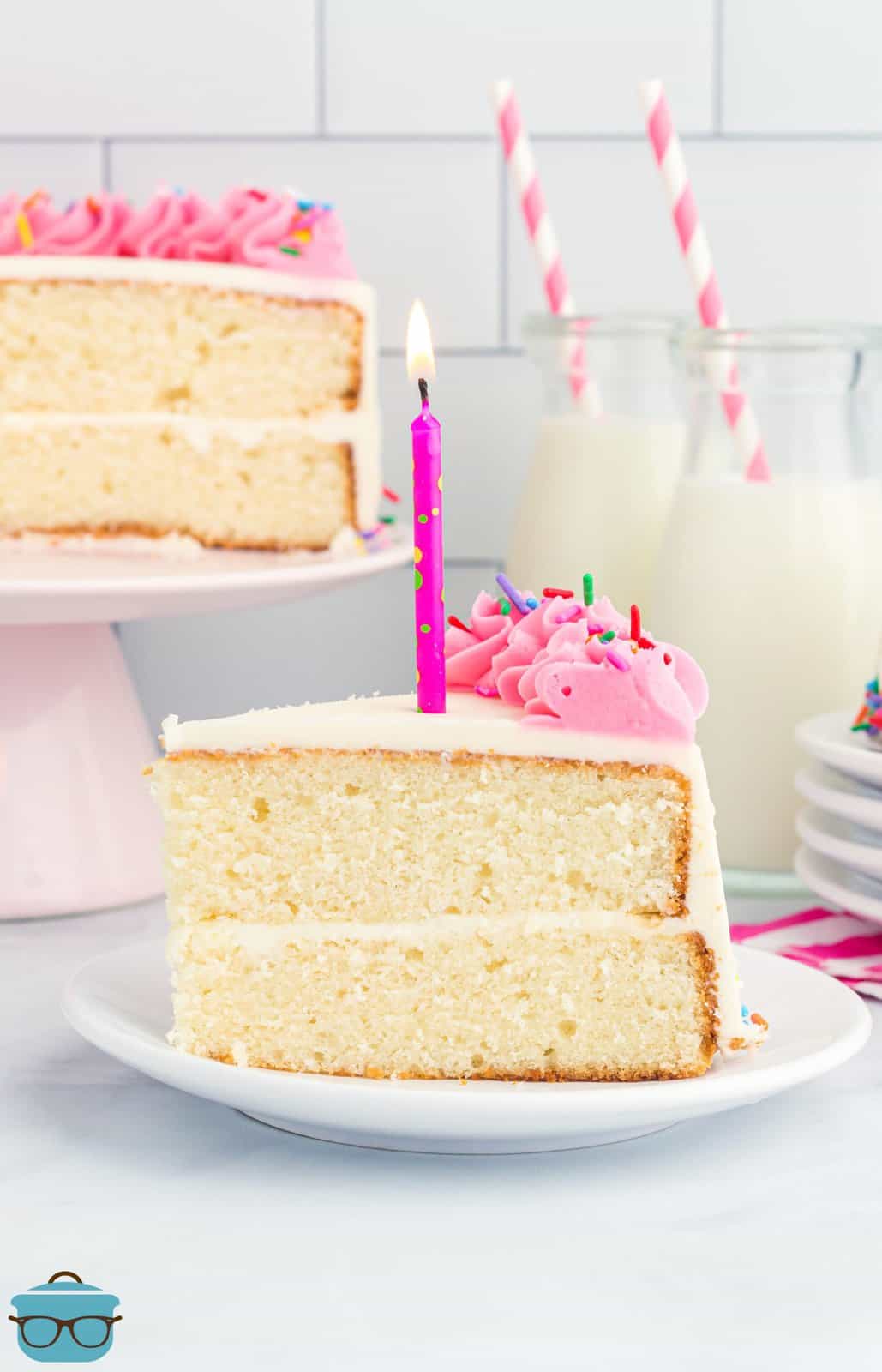 A slice of homemade white cake that is layered and has a homemade frosting and candles on top.