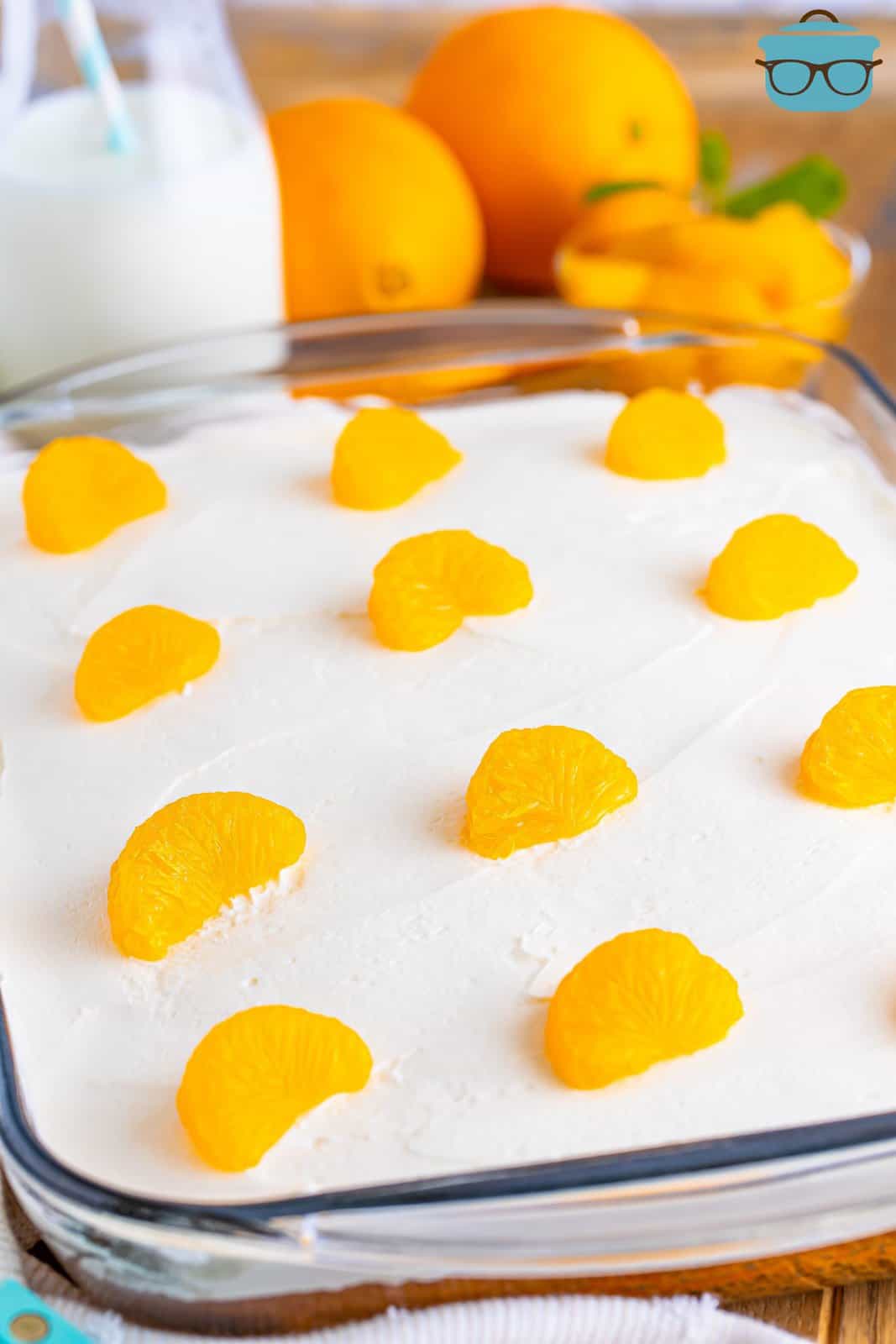 A baking dish with Orange Creamsicle Poke Cake with mandarin oranges on top.