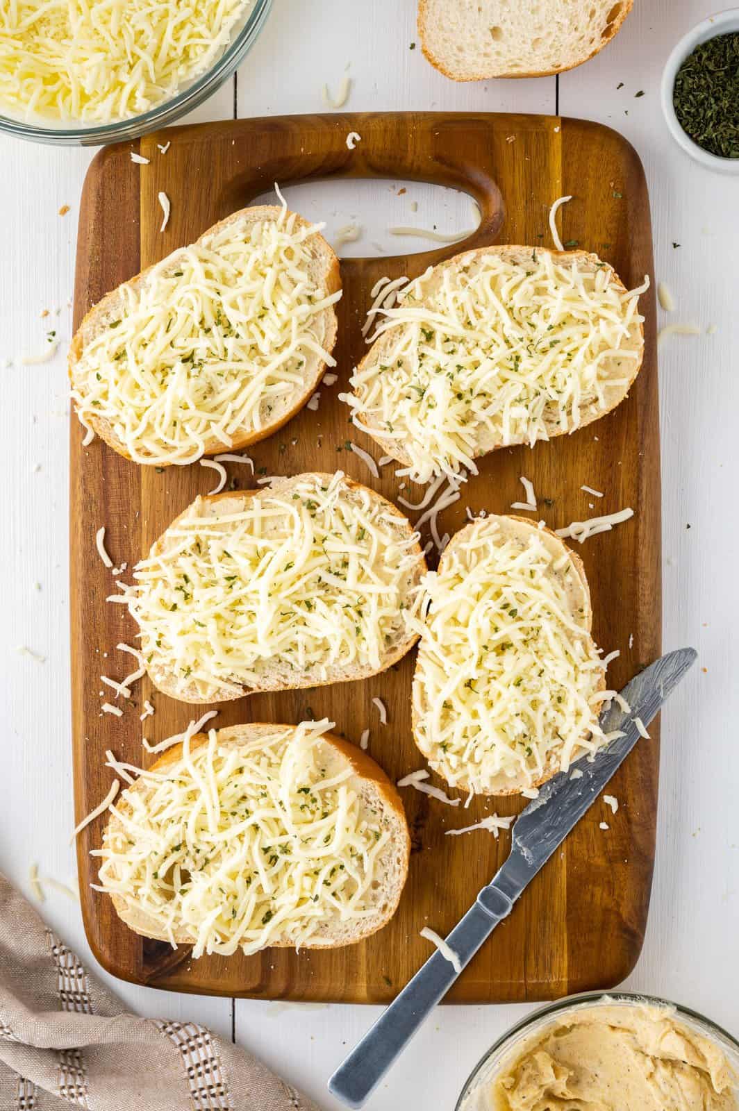Five pieces of bread with garlic butter and mozzarella cheese sprinkled on top. 