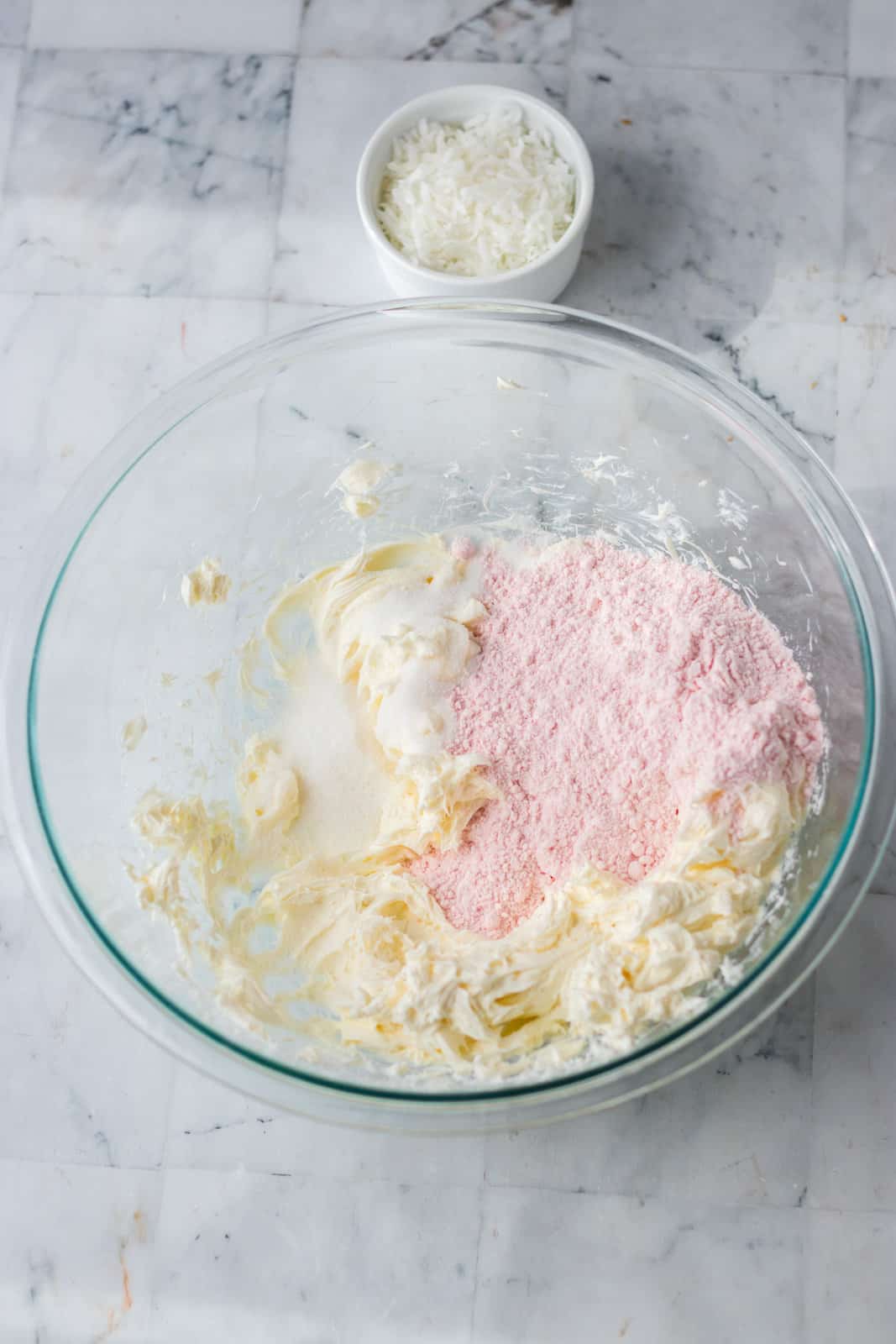 A mixing bowl with cream cheese and strawberry cake mix.