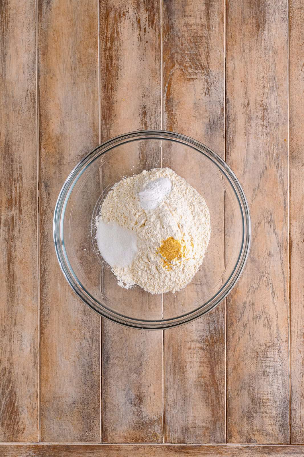 A bowl with flour, baking powder, sugar, and garlic powder.