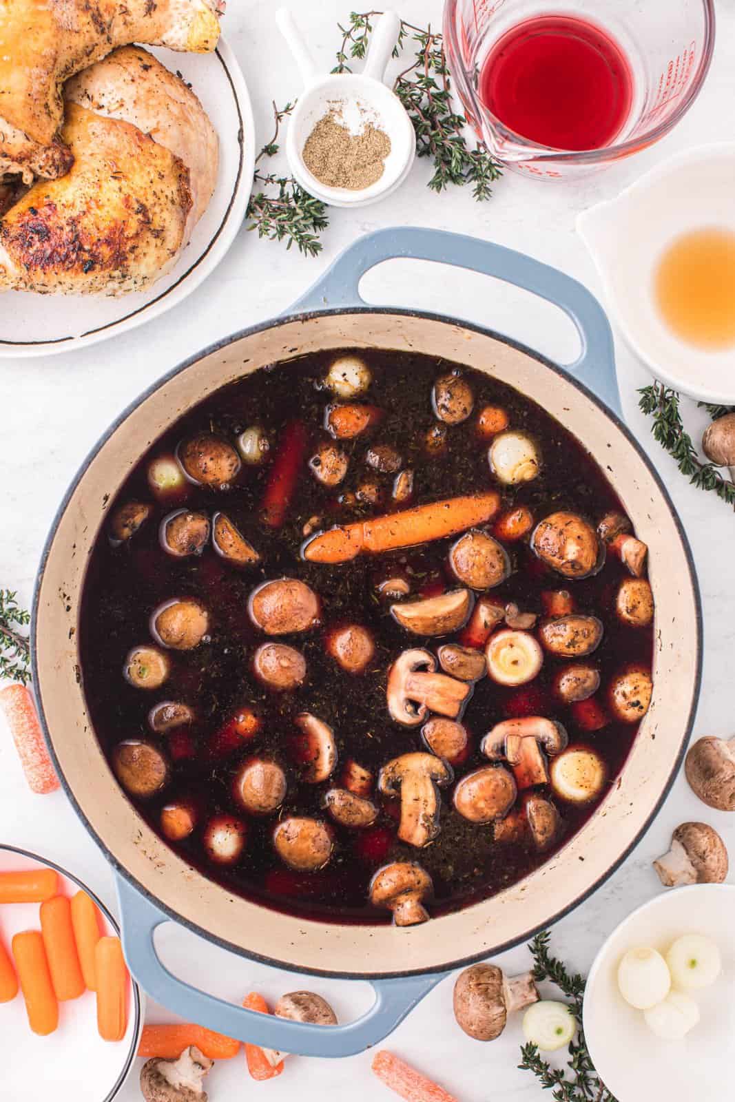 A red wine broth with herbs, spices, carrots, pearl onions, and mushrooms.