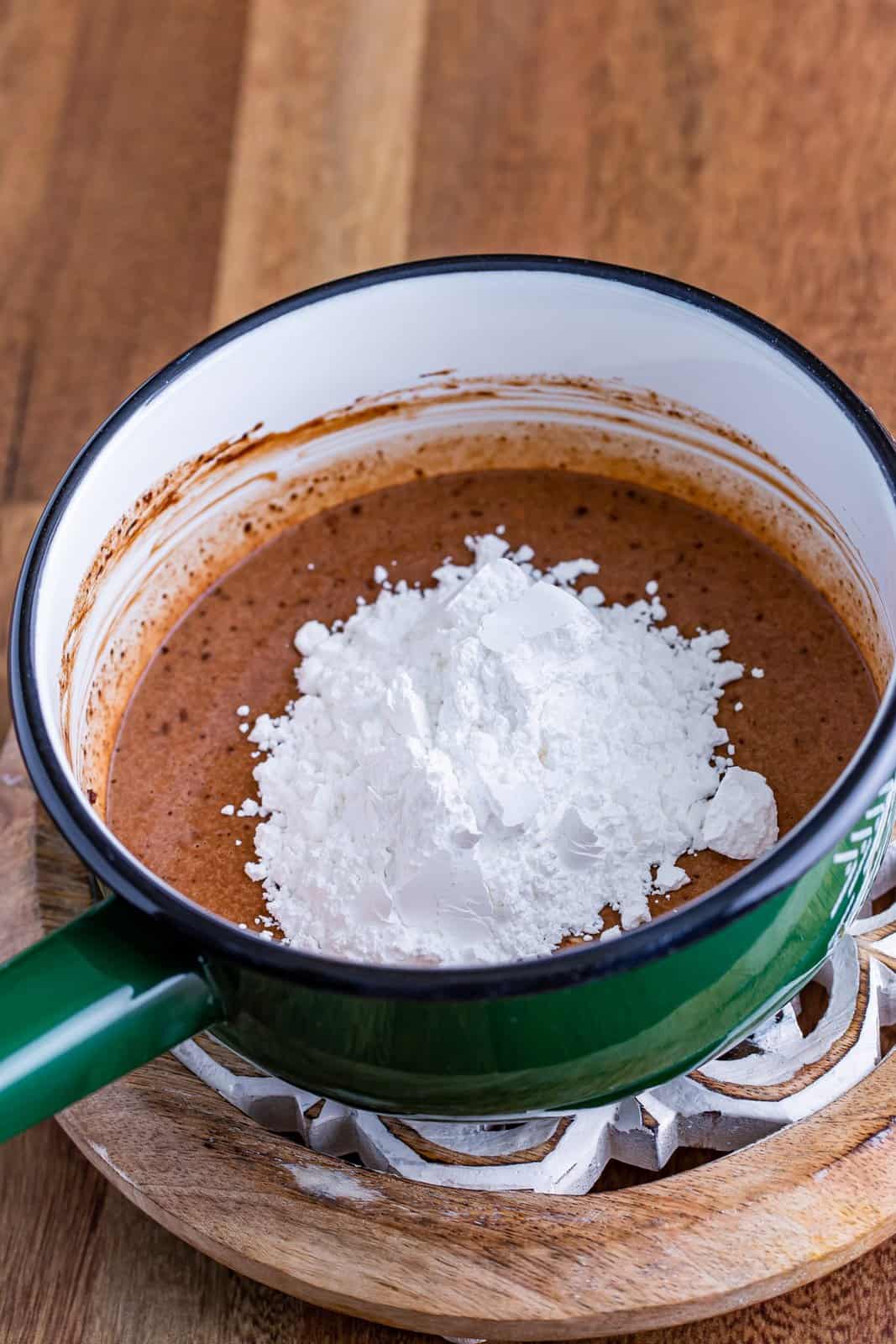 Powdered sugar in a chocolate mixture in a saucepan.