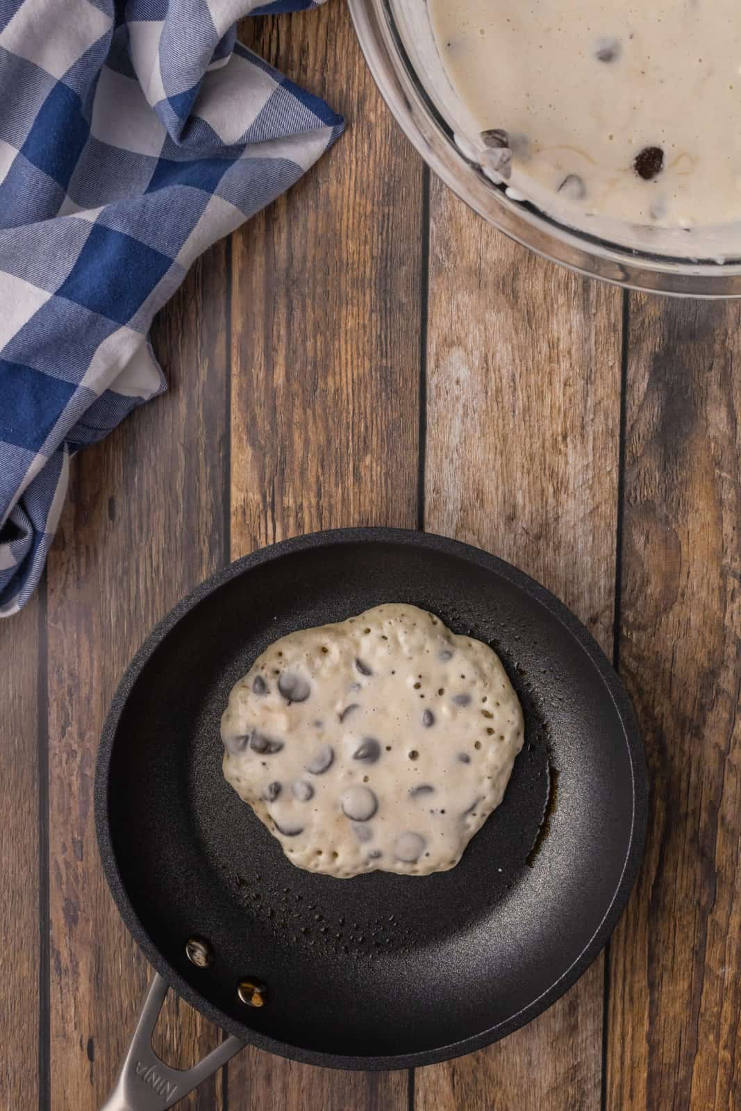 A griddle with pancake batter and chocolate chips. 