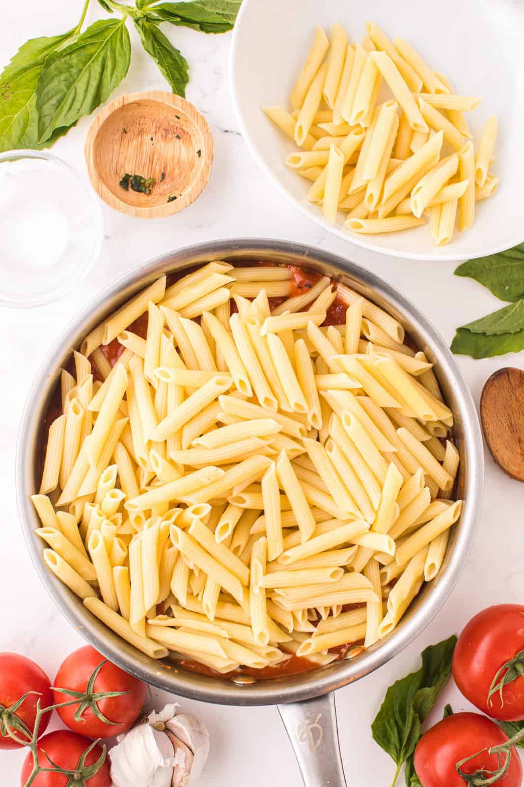 Penne pasta on top of a pot of tomato sauce.