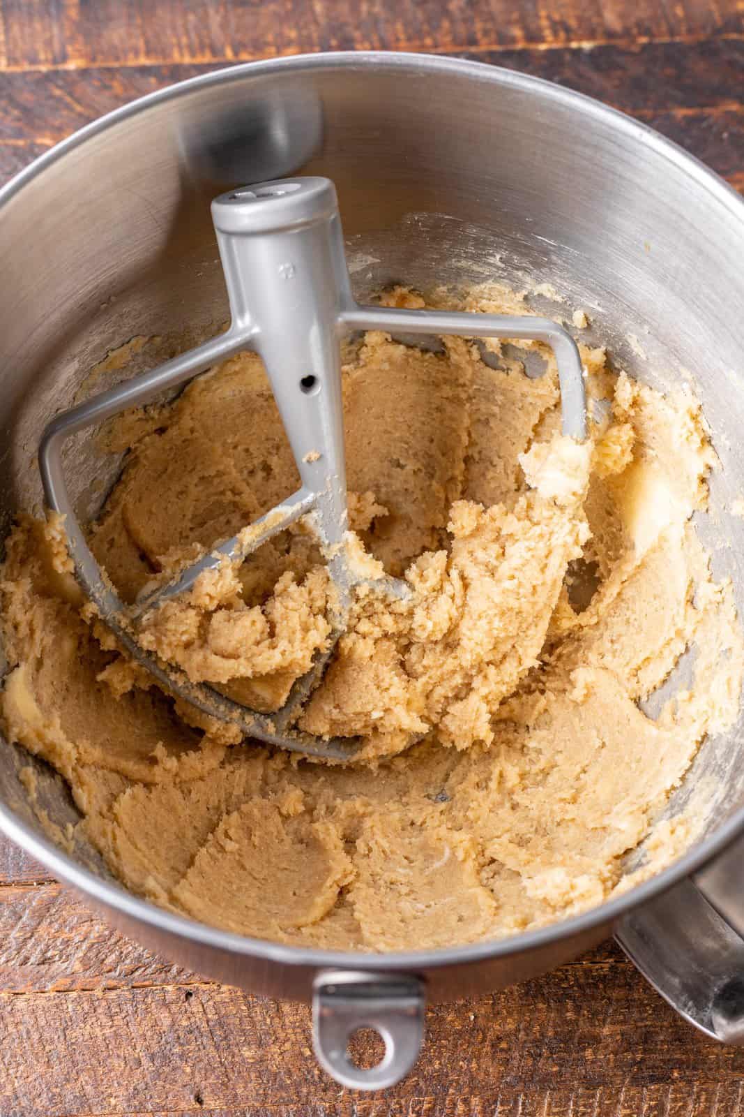 Butter, brown sugar, and granulated sugar being mixed in a mixing bowl.