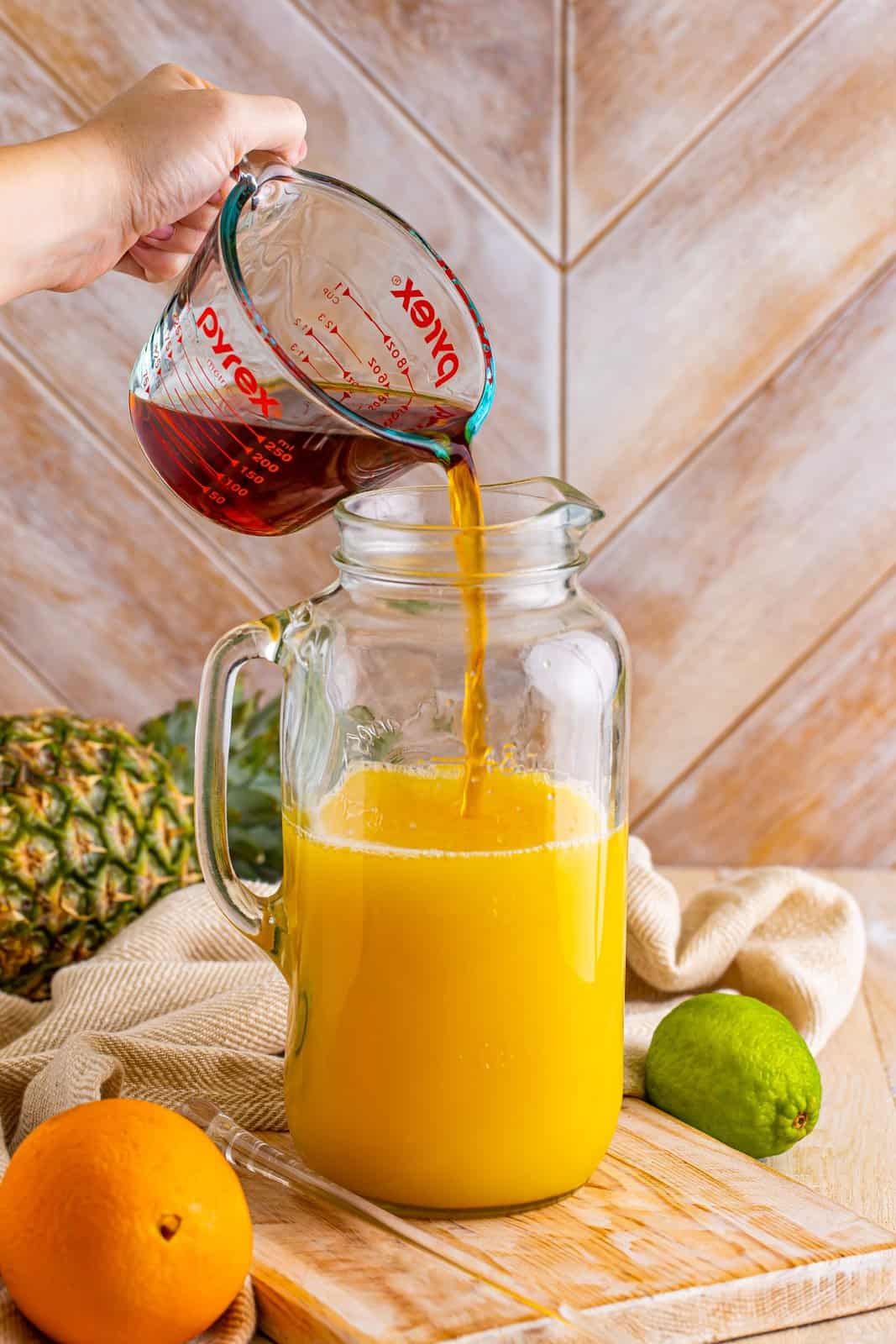 A pitcher with pineapple, orange juice, dark rum, and white rum.