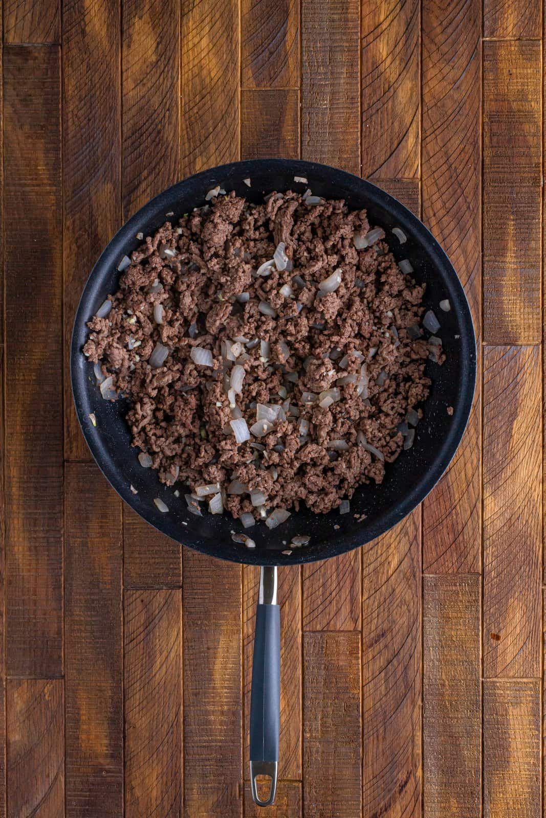 A skillet with cooked ground beef and onion.