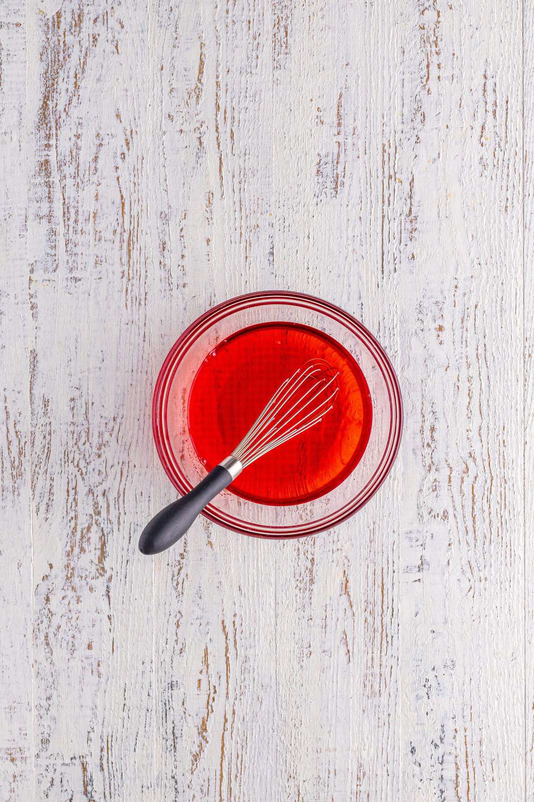 Whisk in a bowl of red gelatin. 