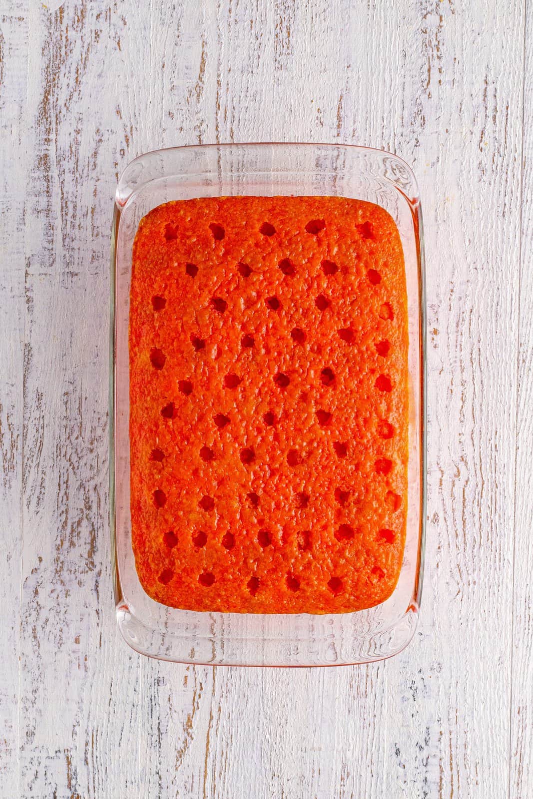 A strawberry cake with holes in it and jello poured in. 