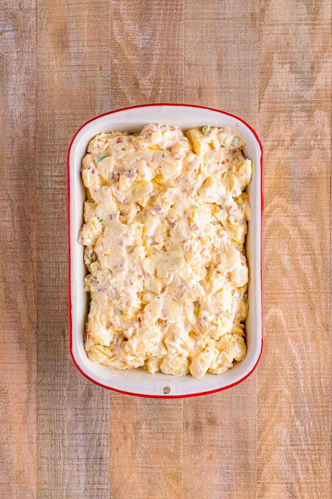 A baking dish with twice baked potato casserole in it waiting on cheese so it can be baked.