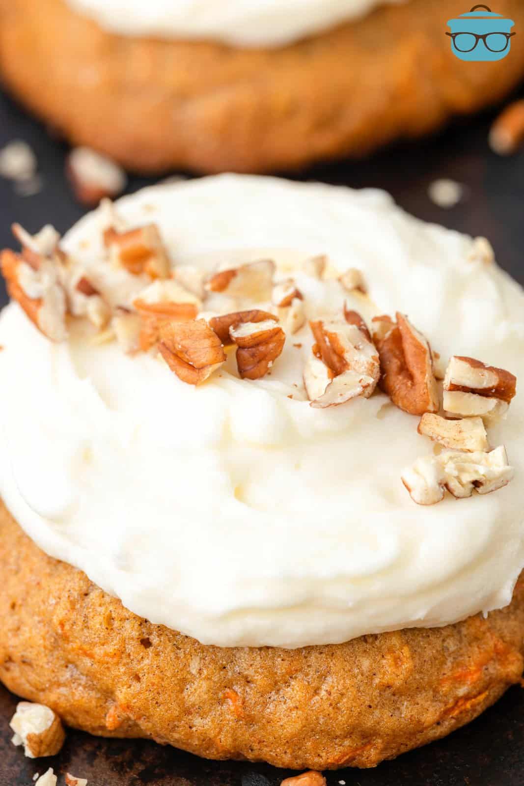 Close up looking at a Carrot Cake Cookie with frosting and chopped nuts on top.