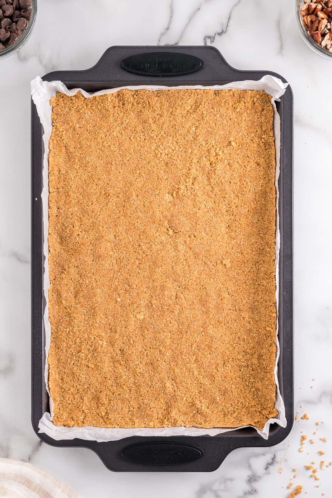 Graham cracker crumb crust on a baking sheet lined with parchment paper.